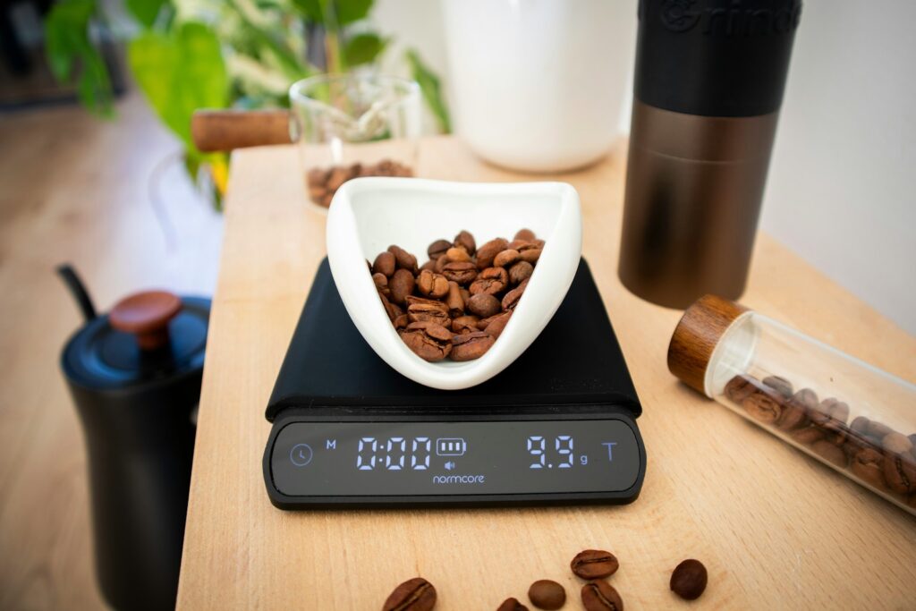 Coffee beans weighed on a digital coffee scale beside a black kettle