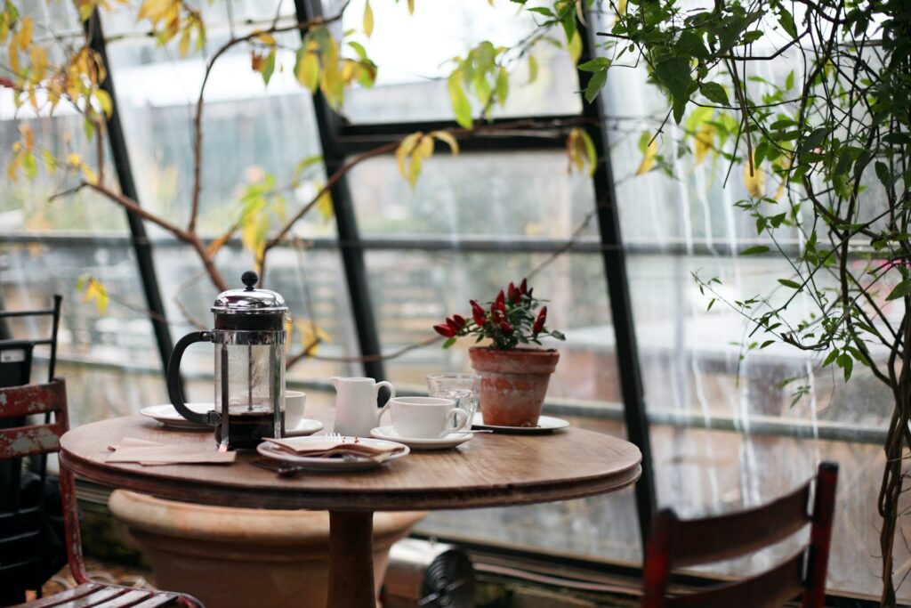 French press on a round wooden table beside a white cup