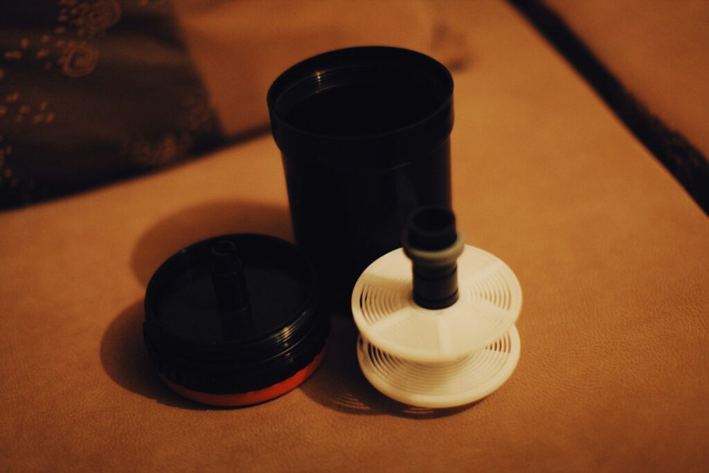 A coffee grinder beside a cup of coffee